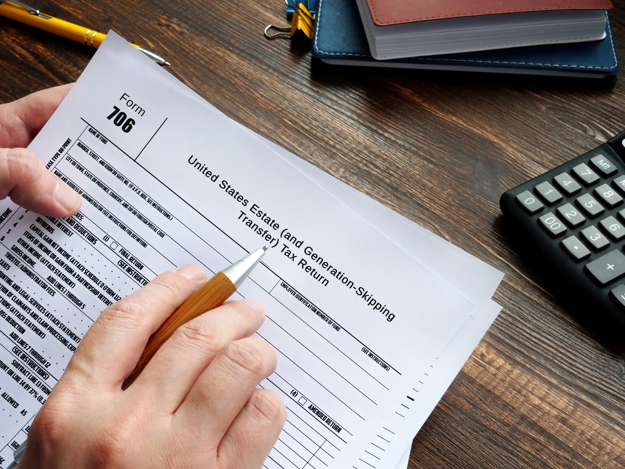 Closeup view of a man's hand holding a pen as he prepares to fill out Internal Revenue Service (I R S) Form 706 to elect portability.